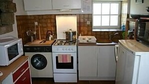 A compact kitchen with a washing machine, a stove, and a microwave. - NEW: Ker Louarn (Ploubezre)