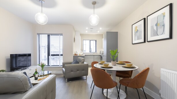 Een moderne woonkamer met een bank, een eettafel met stoelen, een televisie en kunstwerken aan de muur.