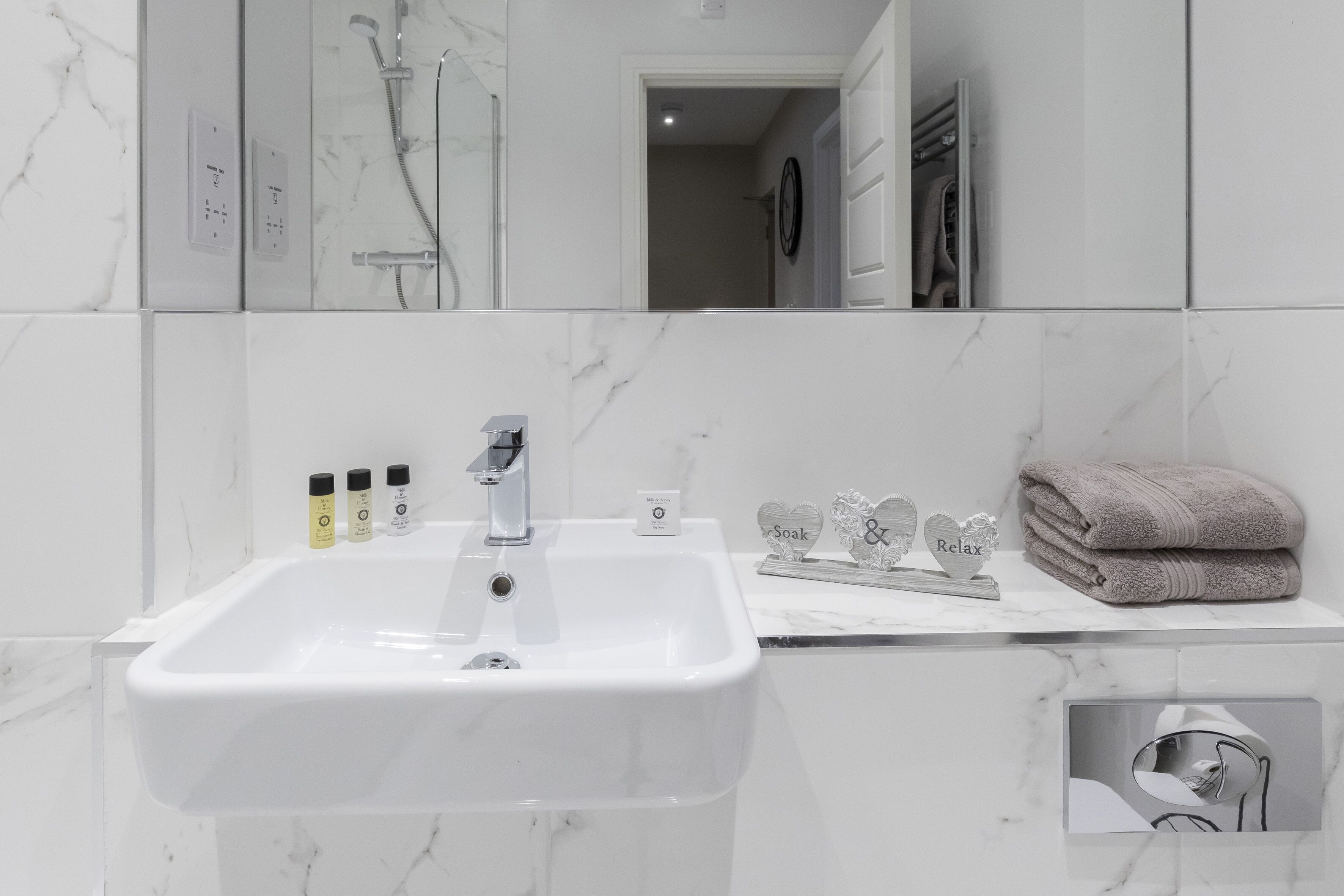 A bathroom with a white sink, a mirror, and a towel rack.