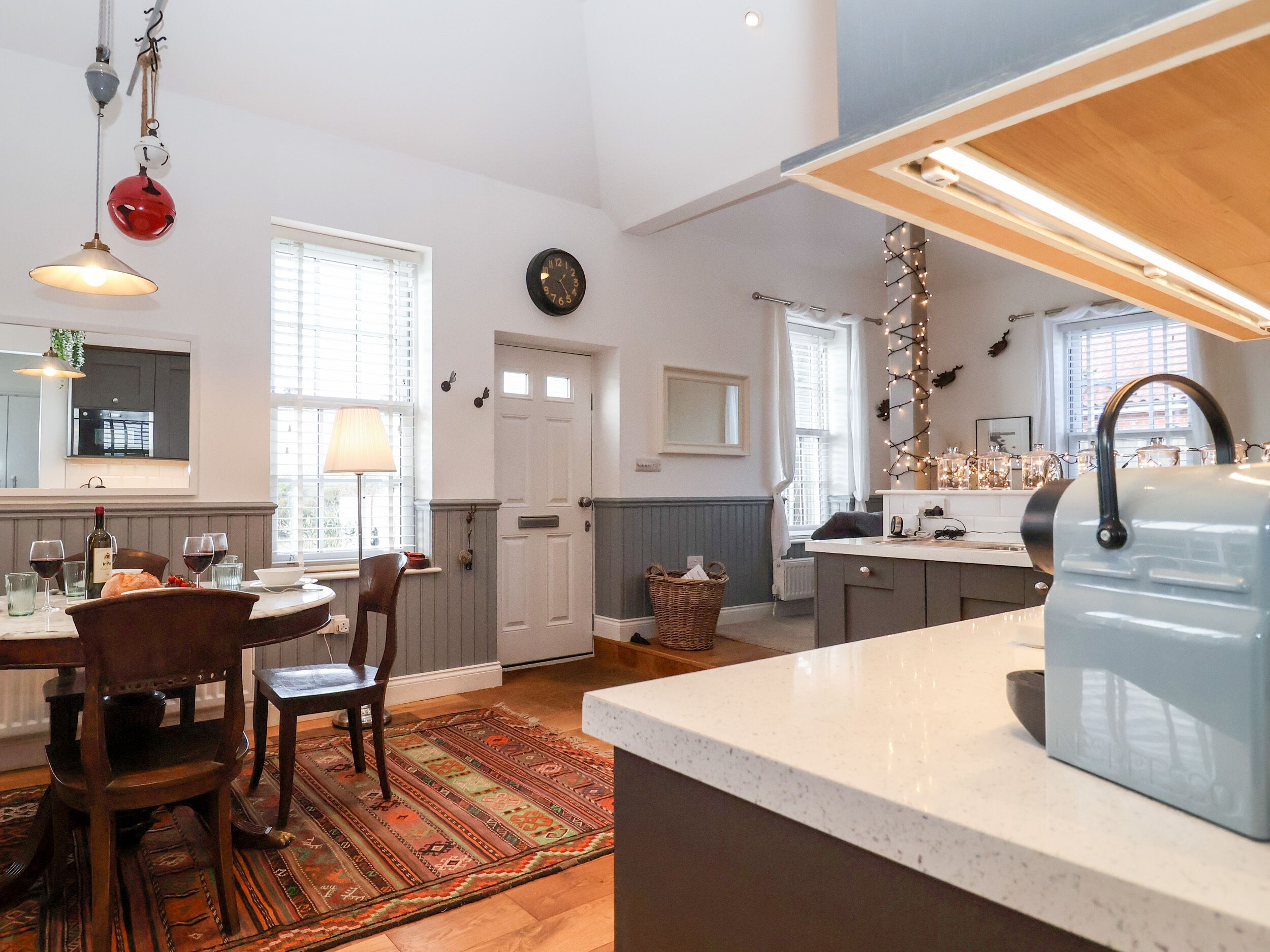 Una cocina moderna con una isla central, sillas de madera, un tapete estampado y una lámpara colgante.