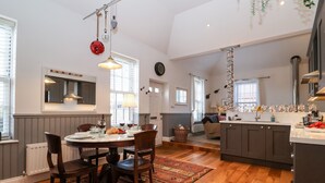 A spacious kitchen with a dining area, wooden flooring, and a large island. - Ebenezer Chapel (Saxmundham)