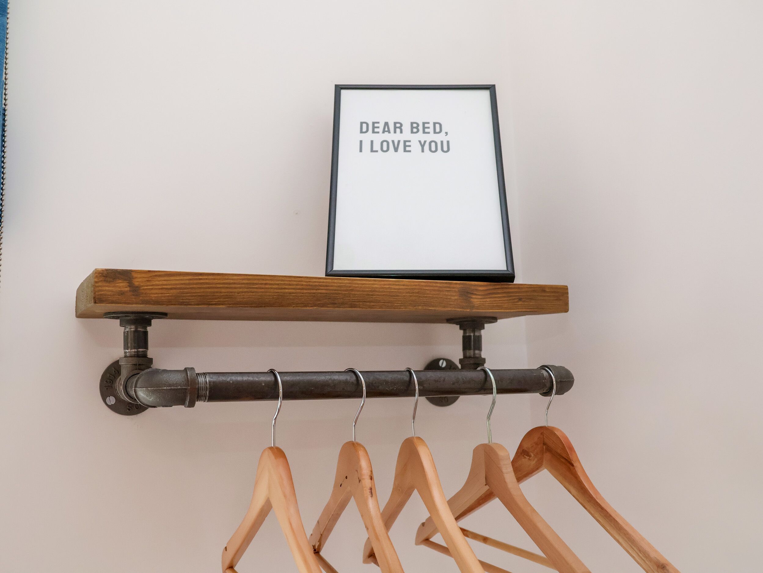 A wooden shelf with a framed sign above it, and several wooden hangers below.