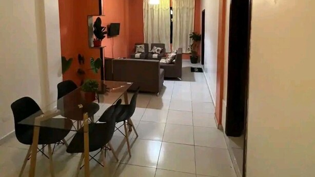 Un salon moderne comprenant un ensemble de canapés, une table à manger avec des chaises et un téléviseur fixé au mur.