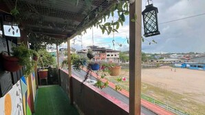 Un balcon abrité, doté d’un revêtement de gazon synthétique, de plantes en pot et offrant une vue sur un terrain de sport.