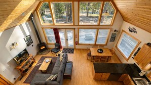 A spacious living area with a fireplace, a sofa, a dining table, and a kitchen with wooden cabinets. - Cascades Adventure Cabin 2 Bedroom Home by NW Comfy Cabins by RedAwning (Leavenworth)