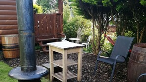 Une terrasse avec un poêle à bois, une table, des chaises et un hamac.