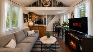 A spacious living area with a sofa, coffee table, and a TV displaying the Netflix logo. - Das Tree Haus 1 Bedroom Home by NW Comfy Cabins by RedAwning (Leavenworth)