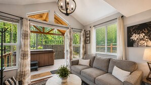 A cozy living room with a sofa, a coffee table, and a hot tub area. - Das Tree Haus 1 Bedroom Home by NW Comfy Cabins by RedAwning (Leavenworth)