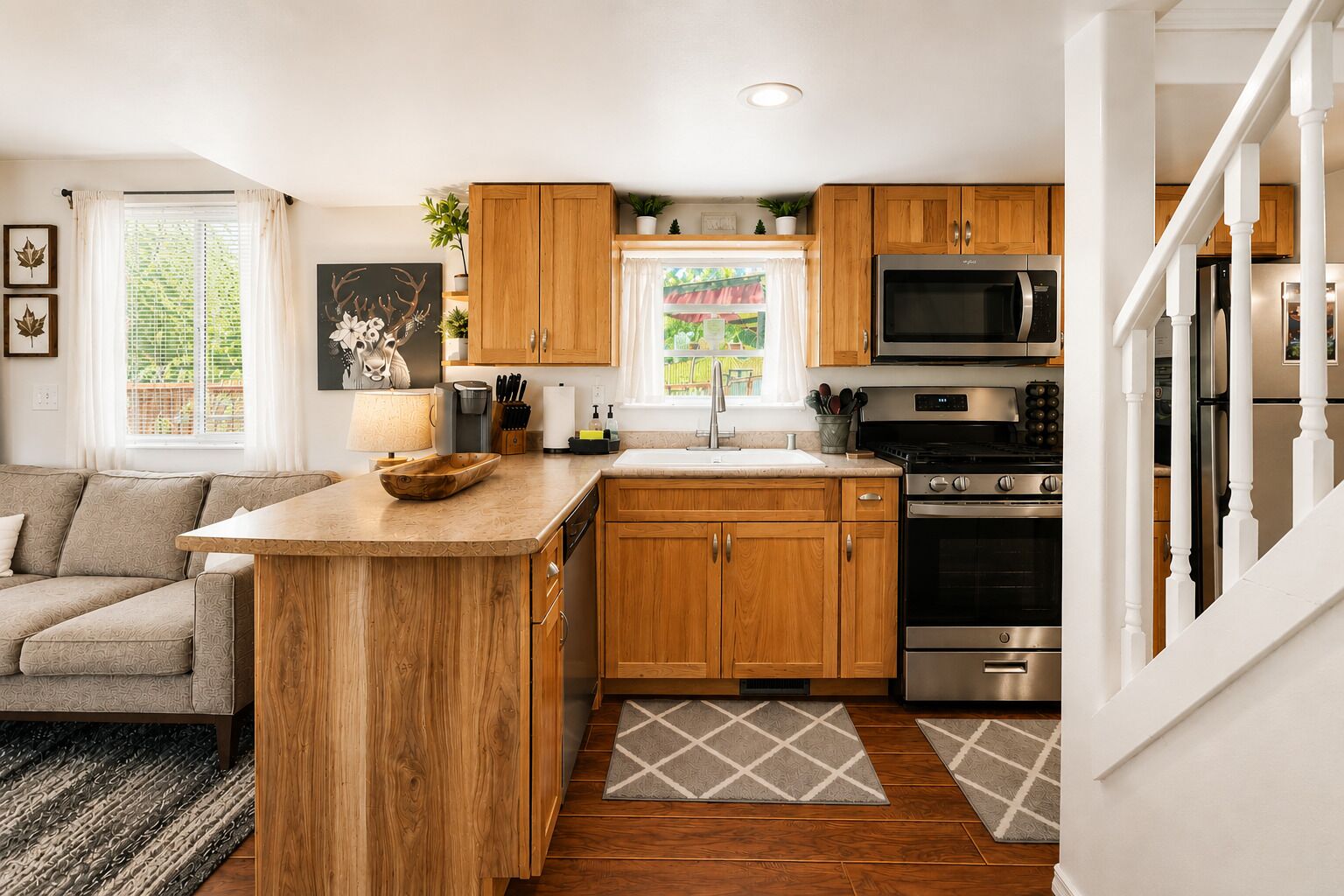 A modern kitchen with wooden cabinets, a central island, stainless steel appliances, and a view to the outside.