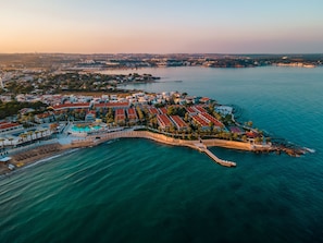 An aerial view of a coastal resort with a marina, a curved walkway, and a large pool area. - Lucas Didim Resort (Didim)