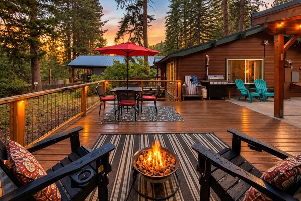 A deck with a fire pit, outdoor seating, and a grill area.