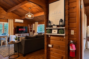 A cozy log cabin interior with a sofa, television, and decorative items.