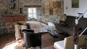 A stone-walled room with a fireplace, a sofa, a leopard-print chair, and a glass coffee table. - Charming detached house with terrace in a farmhouse with swimming pool and garden (Vesseaux)