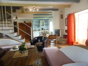 A cozy living area with a sofa, a dining table, and a kitchen in the background. - 17th-century house with a pool in a village in a nature park near Aubenas Vals (Vesseaux)