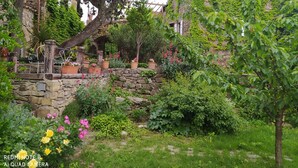 A garden with stone walls, potted plants, and a rustic bench. - Charming detached house with terrace in a farmhouse with swimming pool and garden (Vesseaux)