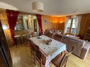 Une pièce chaleureuse comprenant une table à manger, des chaises, un canapé et un coin cuisine.