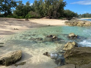 A beach with clear water, rocks, and trees. - Cozy Condo with Pools in Kahuku (Kahuku)