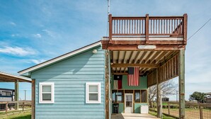 Un bâtiment rustique doté d’un balcon en bois et d’une enseigne indiquant « Maison de plage ».