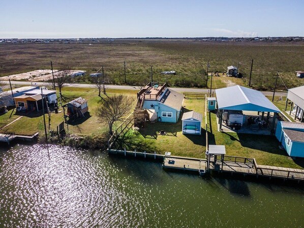 An aerial view of a lakeside property with several buildings, a dock, and a clear view of the surrounding landscape. - Fisherman/woman's Dream, Waterfront 1Bdrm/1Bath Home (Bay City)