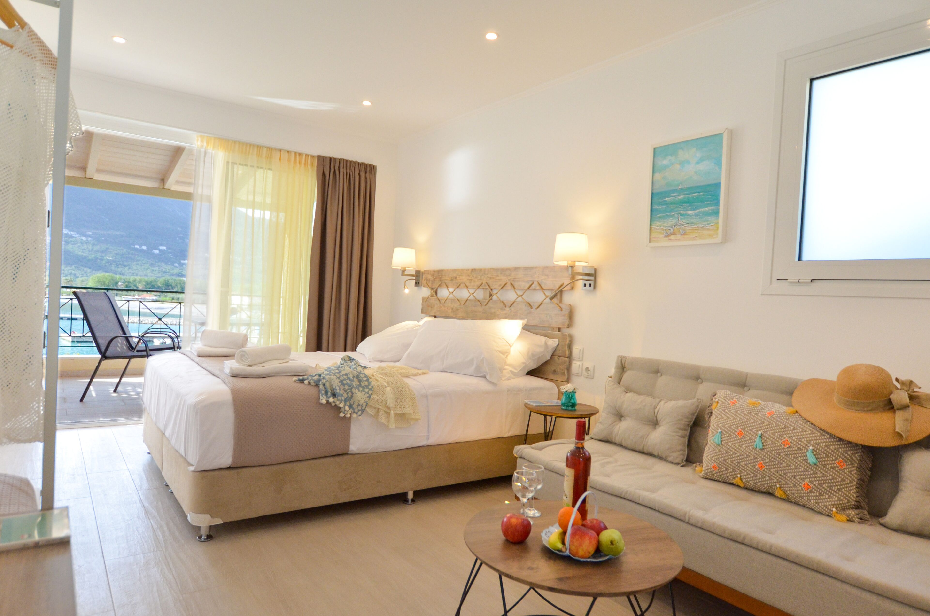 A bedroom with a bed, a sofa, a table with fruit, and a balcony with a chair.