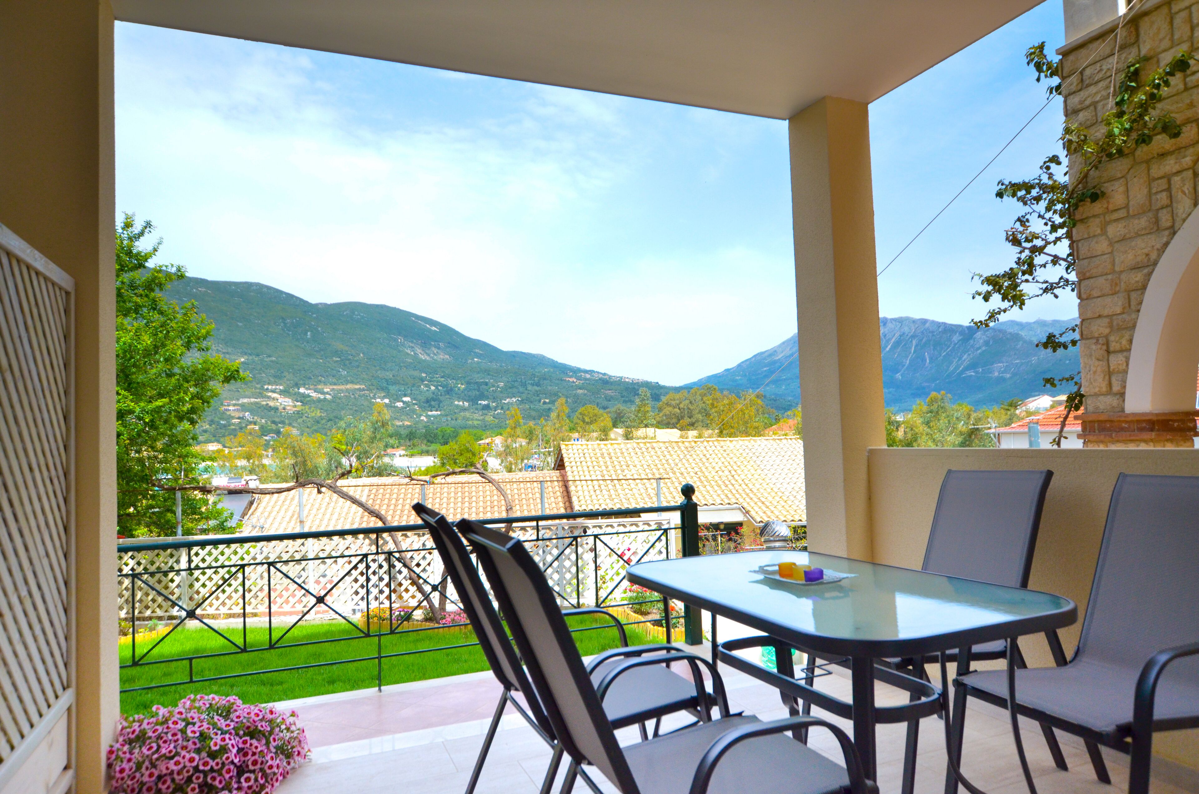 A balcony with a table and chairs, overlooking a mountainous landscape.