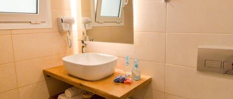 A bathroom with a white sink, a mirror above it, a toilet, and a window.