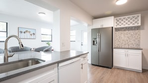 A modern kitchen with white cabinetry, a stainless steel refrigerator, and a dishwasher. - 🏖️4 BR Canal Front Oasis- 1.5 Miles to Downtown! (Naples)