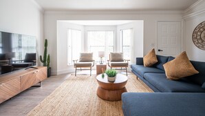 A modern living room with a blue sofa, two armchairs, a wooden coffee table with a plant, a TV, and a cactus. - 🏖️4 BR Canal Front Oasis- 1.5 Miles to Downtown! (Naples)