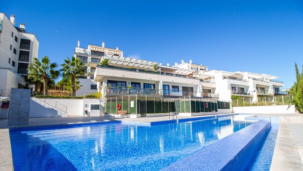 A swimming pool with a clear blue water surface, surrounded by modern buildings with balconies and a lifebuoy on the poolside. - 3082 RES LOMAS DE CAMPOAMOR (Orihuela Costa)