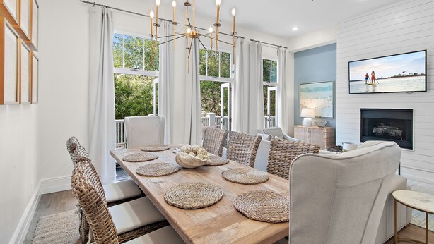 A dining room with a wooden table, woven chairs, and a chandelier.
