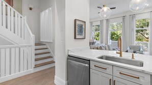A modern kitchen with a dishwasher, white cabinets, and a large window.