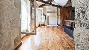 Une pièce spacieuse avec des poutres apparentes, des murs en pierre et un plancher en bois.