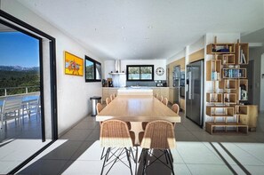 Una cucina moderna con un'isola grande, zona pranzo con sedie e vista sulle montagne.