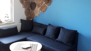 A modern living room with a stone accent wall, a blue sofa, and a round wooden coffee table.