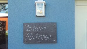 A chalkboard sign reading "Blauer Matrose" mounted on a blue wall, above a white door.