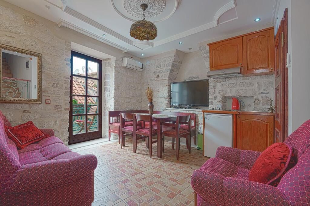 Una sala de estar acogedora con chimenea, un comedor con mesa y sillas, y una cocina con armarios de madera y televisor.