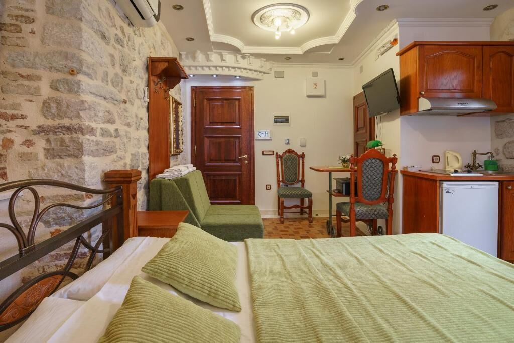 Una habitación con cama, escritorio, silla, televisión y kitchenette.