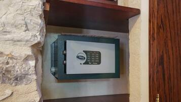 A Viro safe mounted on a textured wall with a wooden shelf above it.