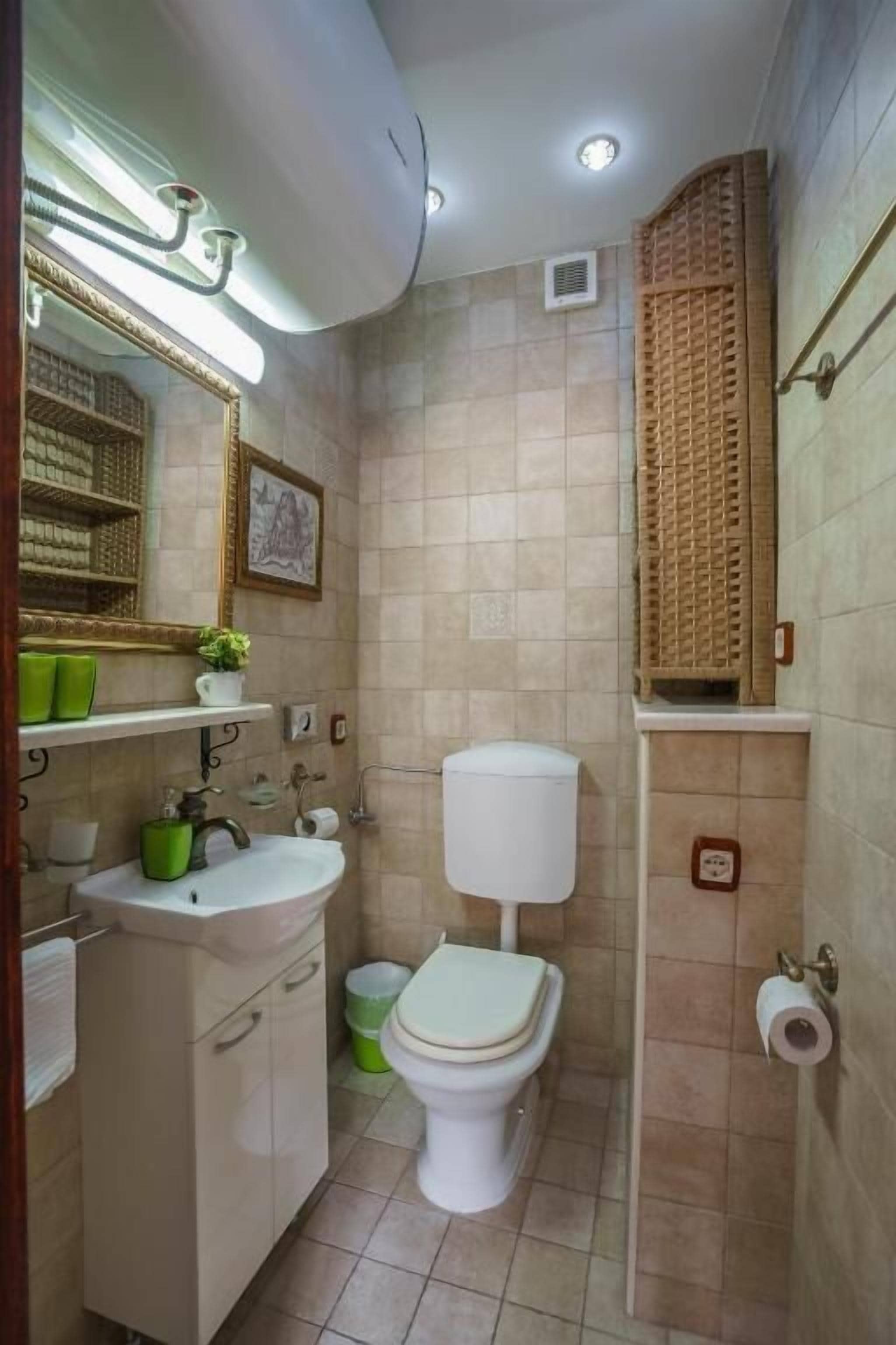 Un baño pequeño con un lavamanos blanco, un inodoro y un espejo.
