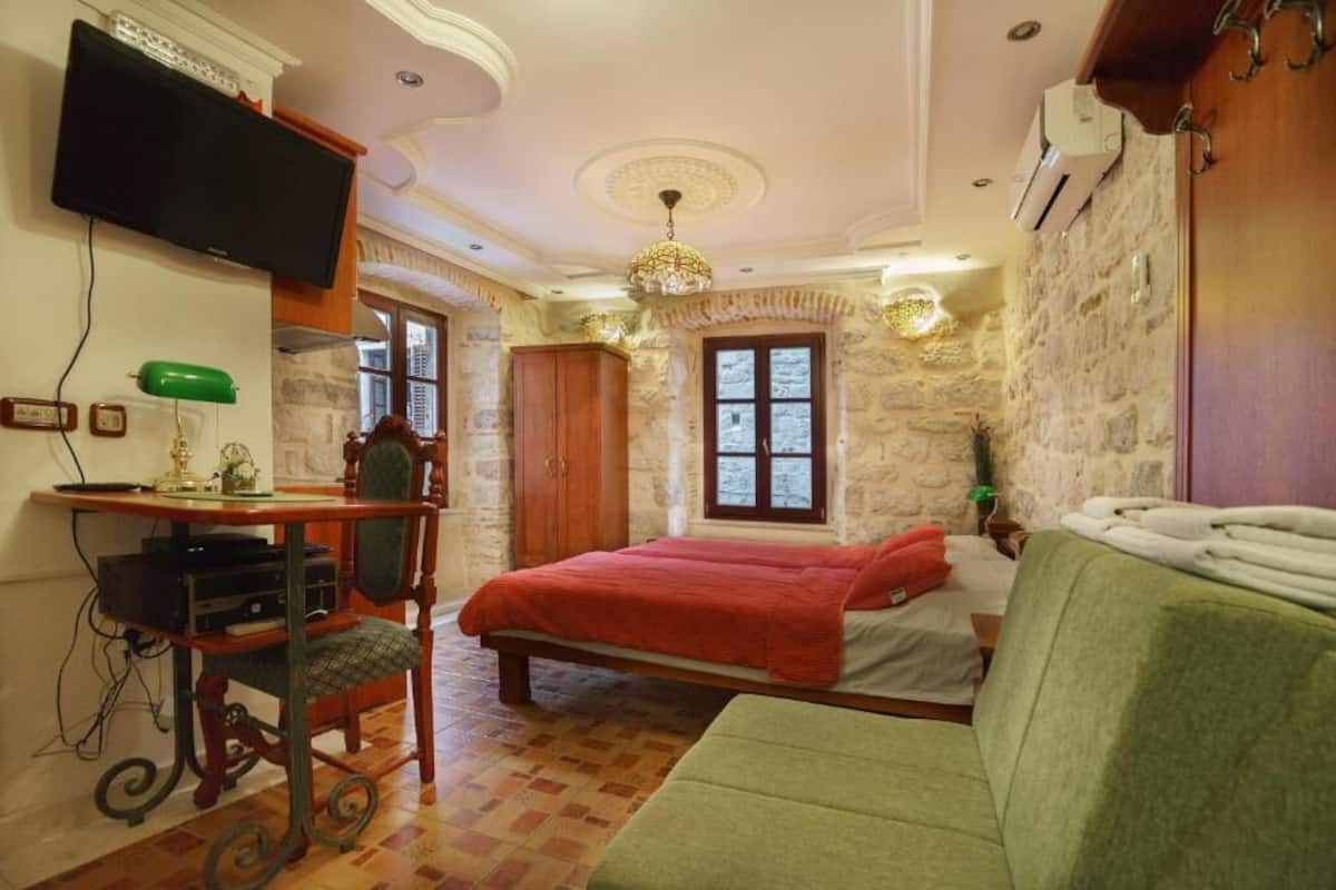 Une chambre à coucher avec un lit, un bureau avec un ordinateur, une télévision et un canapé vert.