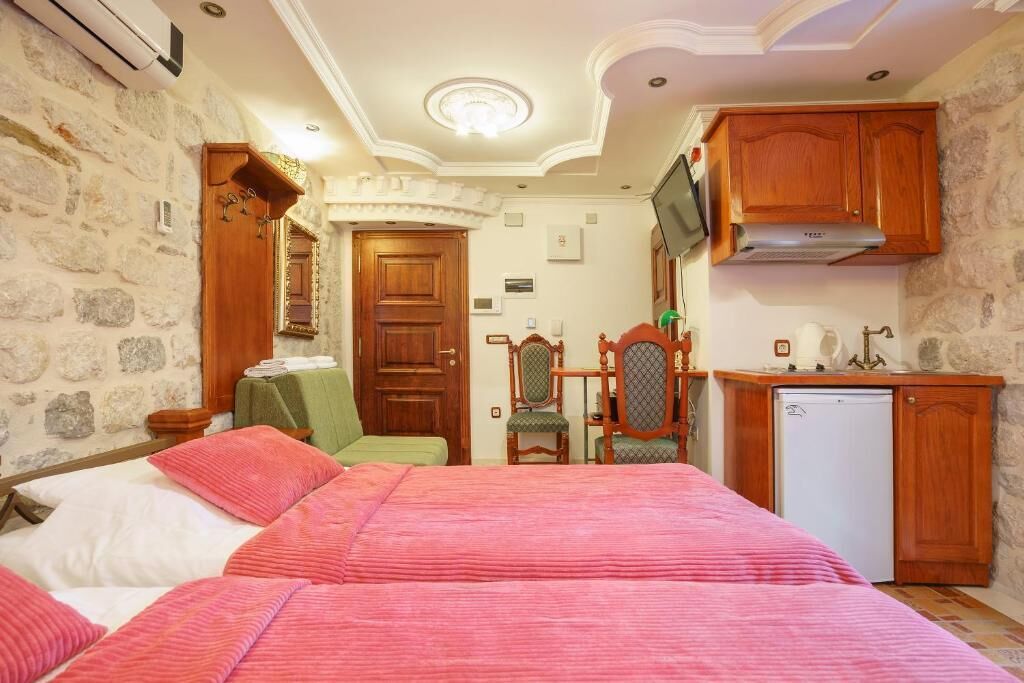 Un dormitorio con dos camas, un armario de madera, un televisor y una pequeña cocina.
