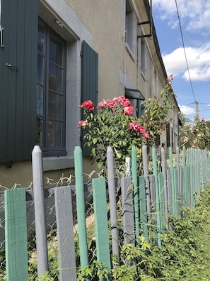 Une maison avec une clôture en bois et un rosier devant.