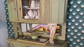 A two-tiered, green-painted cabinet with ornate carvings and a glass-fronted upper shelf. - Alfred and George, The Appendix (Sainpuits)