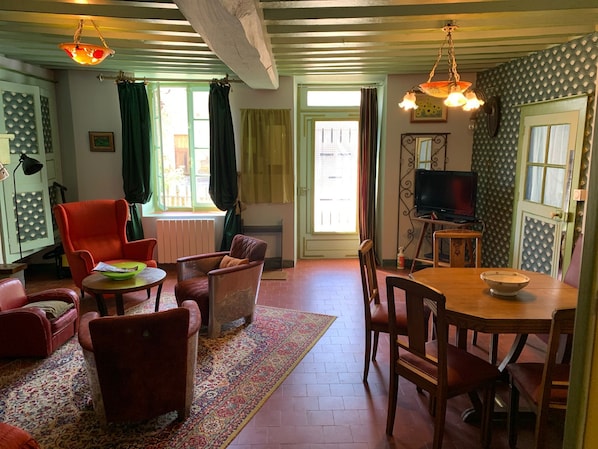 Un salon chaleureux avec une cheminée, un téléviseur et un coin repas comprenant une table et des chaises.
