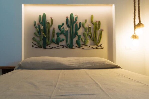 A bed with a headboard featuring a cactus wall art. - Vanilla House Design, Garage, Wifi (Sestri Levante)