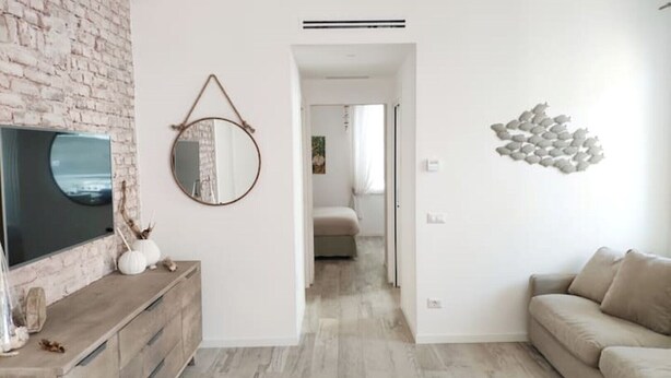A modern living room with a brick wall, a flat-screen TV, a round mirror, and a decorative wall piece. - Vanilla House Design, Garage, Wifi (Sestri Levante)