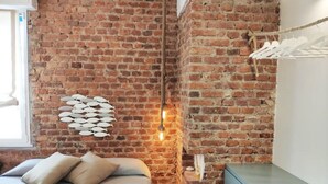 A room with a brick wall, a bed with pillows, a wall-mounted fish decoration, and a hanging clothes rack. - Vanilla House Design, Garage, Wifi (Sestri Levante)