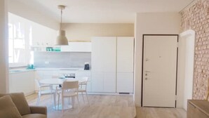 A modern kitchen with white cabinets, a dining area with a table and chairs, and a beige sofa. - Vanilla House Design, Garage, Wifi (Sestri Levante)