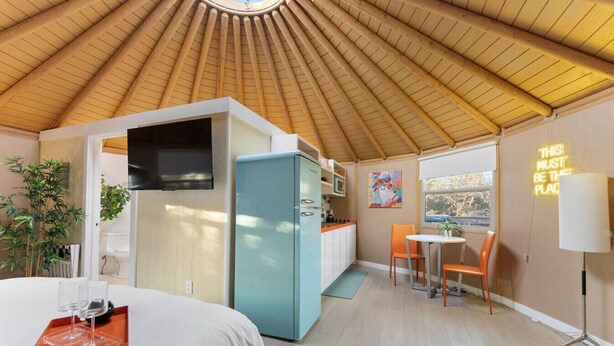 A compact room with a bed, a kitchenette, a dining area, and a large window. - Hippy Chick Yurt Cabin (Saint Jo)