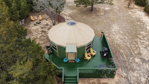 A circular building with a green deck, a fire pit, and outdoor seating. - Hippy Chick Yurt Cabin (Saint Jo)